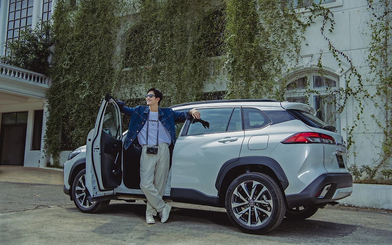 Chàng trai áo sơ mi xanh đứng bên cạnh xe Toyota