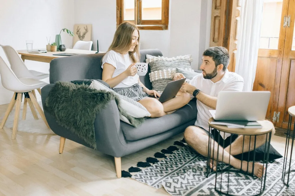Cặp đôi ngồi làm việc trên laptop ở sofa phòng khách