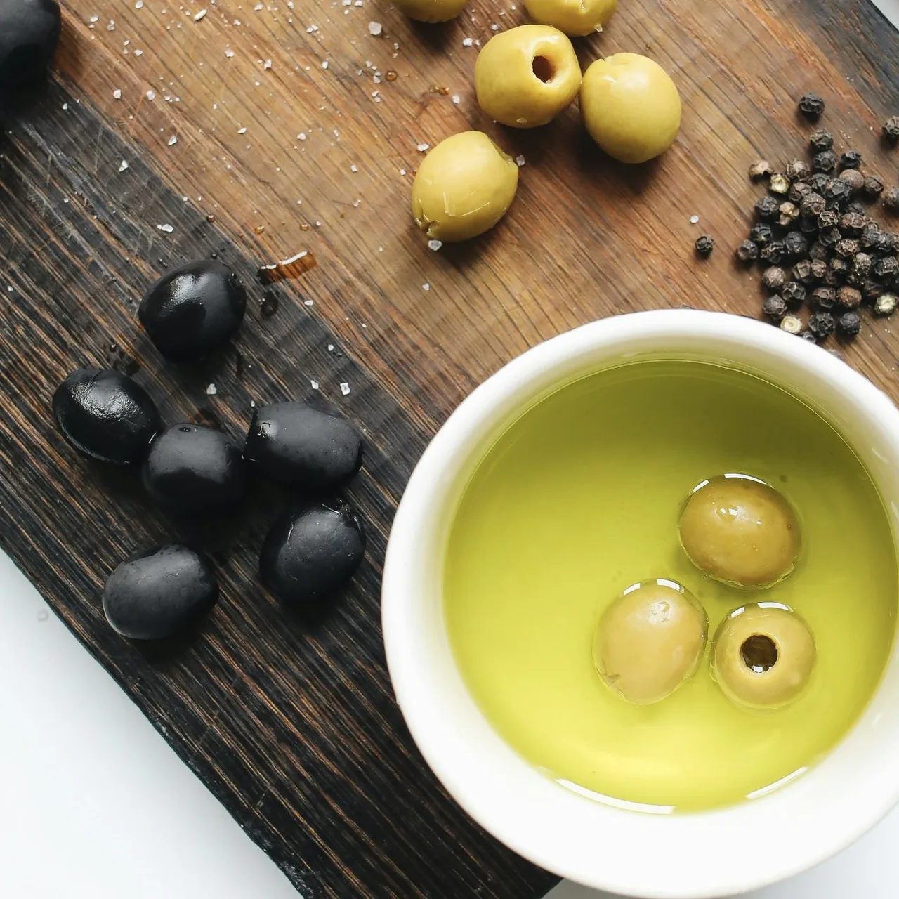 Bát nhỏ chứa dầu olive đen cùng vài quả olive.