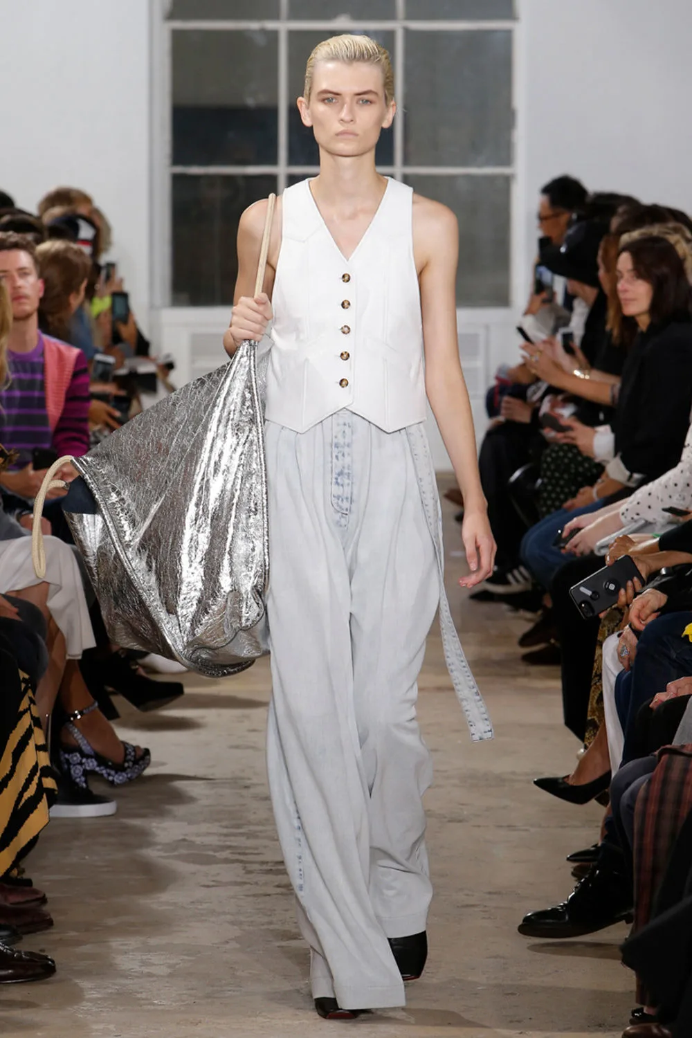 Người mẫu mặc áo trắng mang túi xách to màu bạc Proenza Schouler