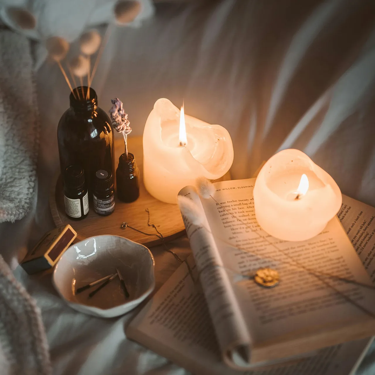 Nến trắng đặt cạnh cuốn sách dùng để thanh tẩy năng lượng xấu khỏi ngôi nhà