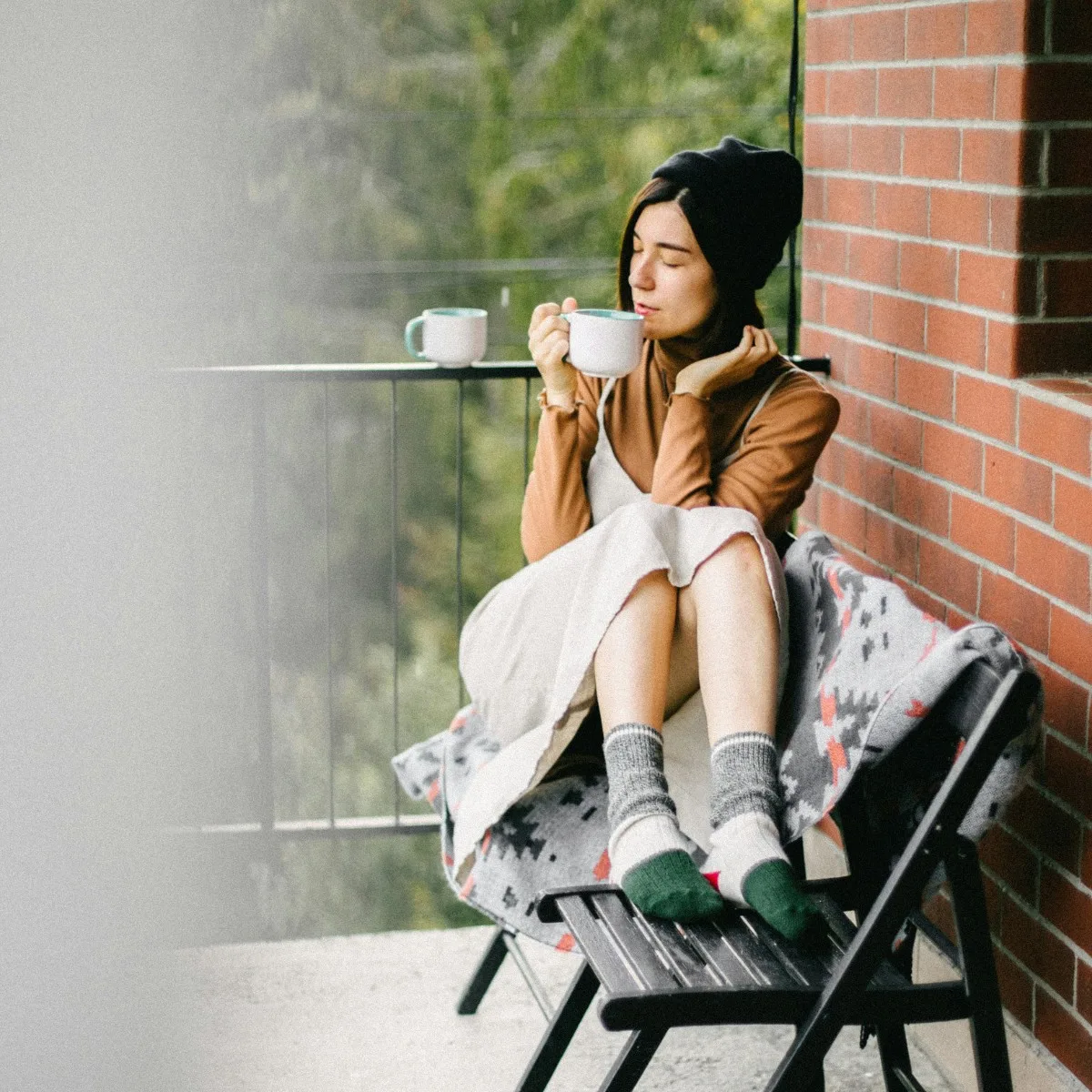 Cô gái mặc đầm yếm đội mũ len ngồi trên ghế xếp uống cà phê ngoài bàn công theo phương pháp 5-4-3-2-1