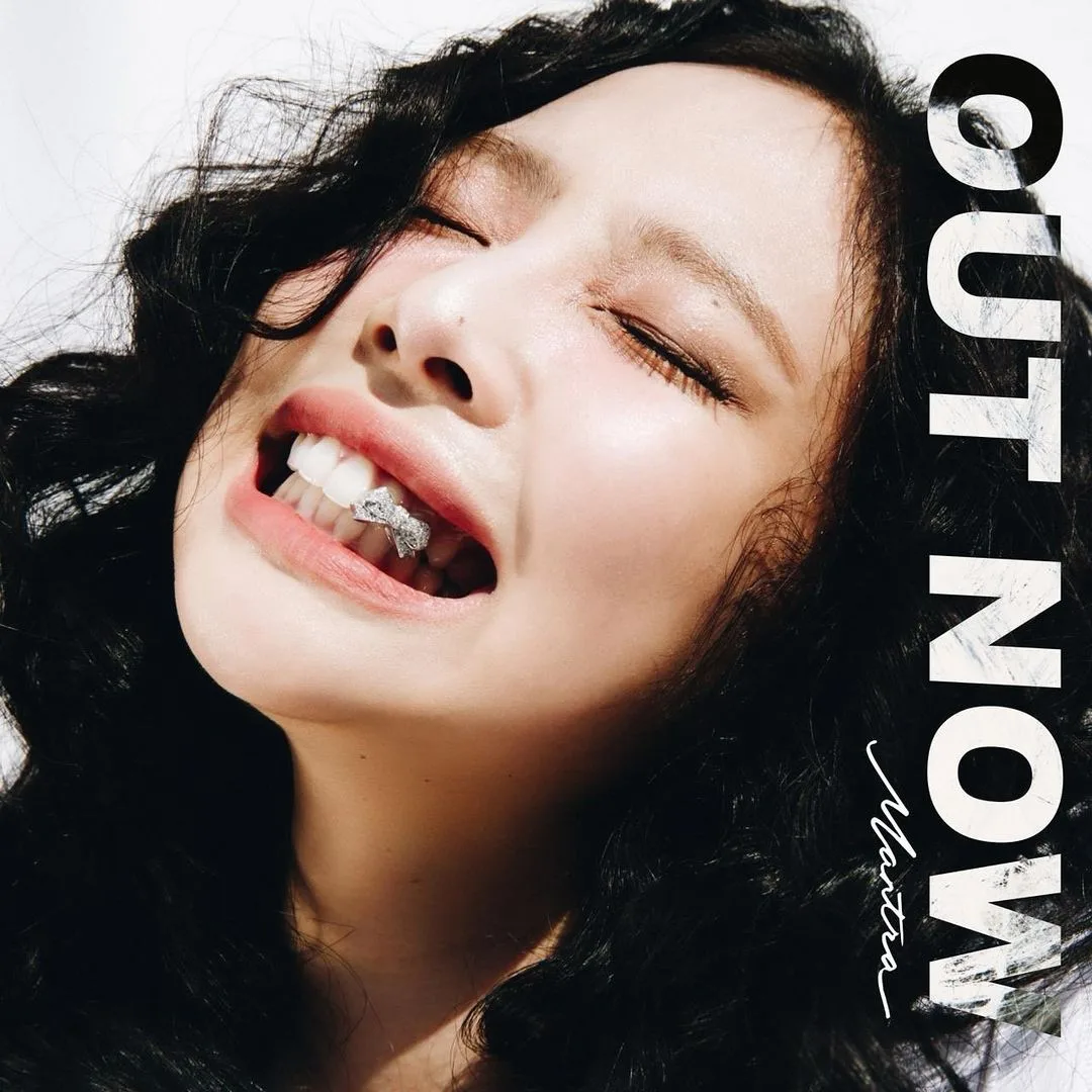 Jennie tạo dáng cười tươi và đính đá hình nơ màu bạc trên răng trong poster MV Mantra