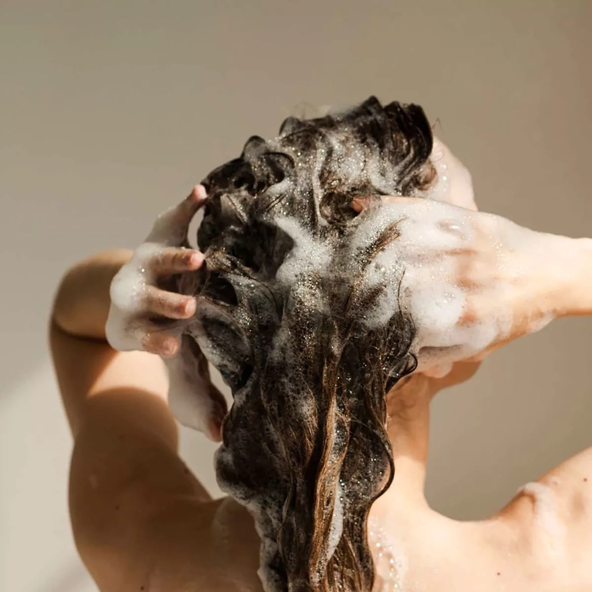 Cô gái đang gội đầu không chứa sulfate giúp chăm sóc tóc.