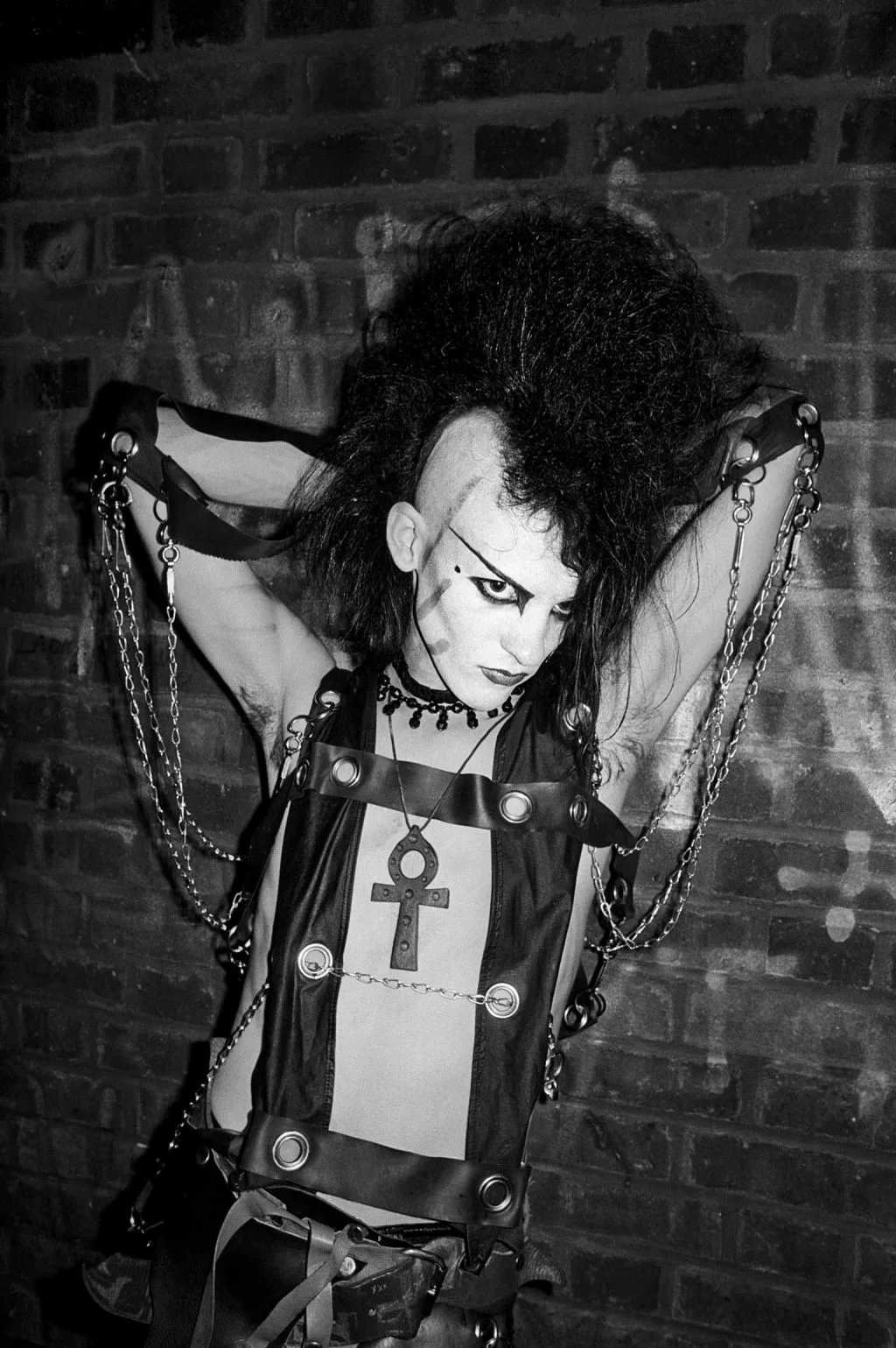 Goth man posing in front of a wall in black and white 1980s
