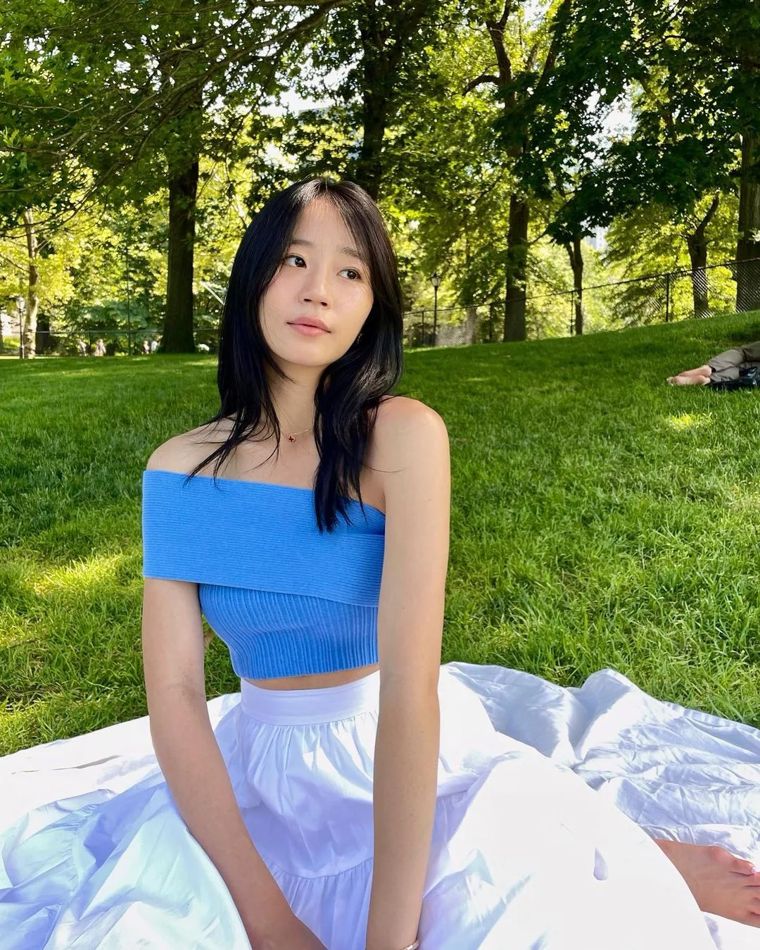 gen-z-ua-chuong-xu-huong-lam-dep-ben-vung Gen Z - cô gái châu Á tóc đen dài xõa thẳng, mặc áo hở vai màu xanh dương và ngồi trên thảm cỏ