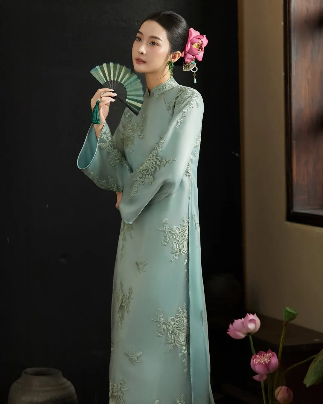 Sự kết hợp đồng điệu giữa sắc hồng của đóa hoa lụa và họa tiết thêu tay trên tà áo dài.