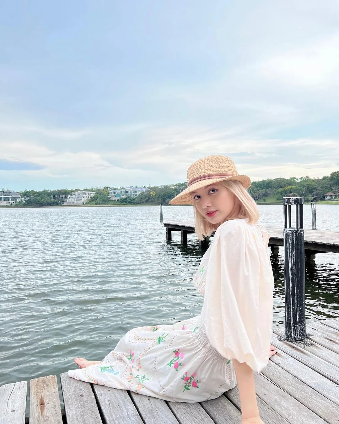 Lisa BLACKPINK đội mũ rộng vành ngồi bên bờ hồ