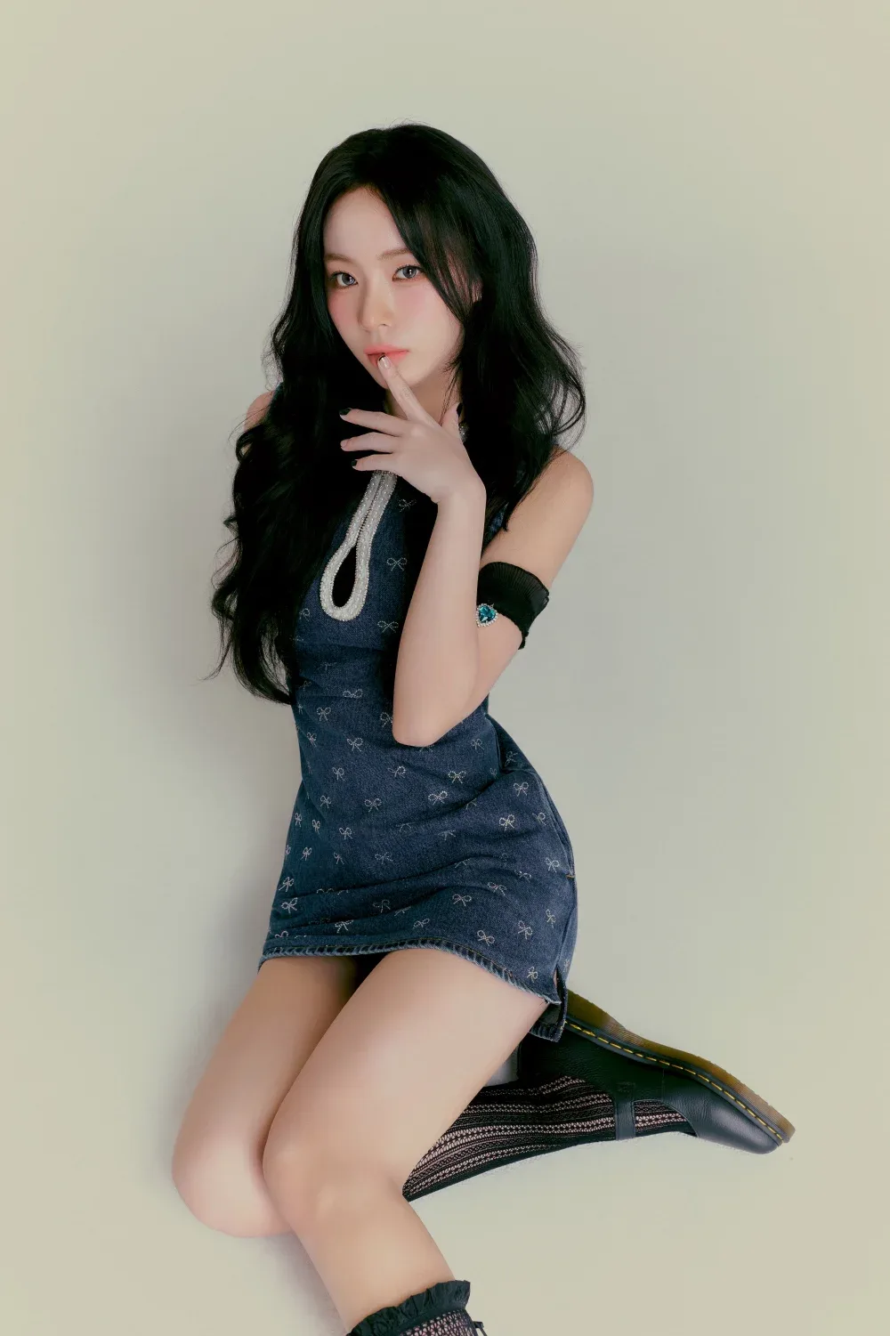 SHUIE SAY MY NAME tạo dáng ngồi trên sàn, trang phục denim và tóc dài uốn nhẹ.