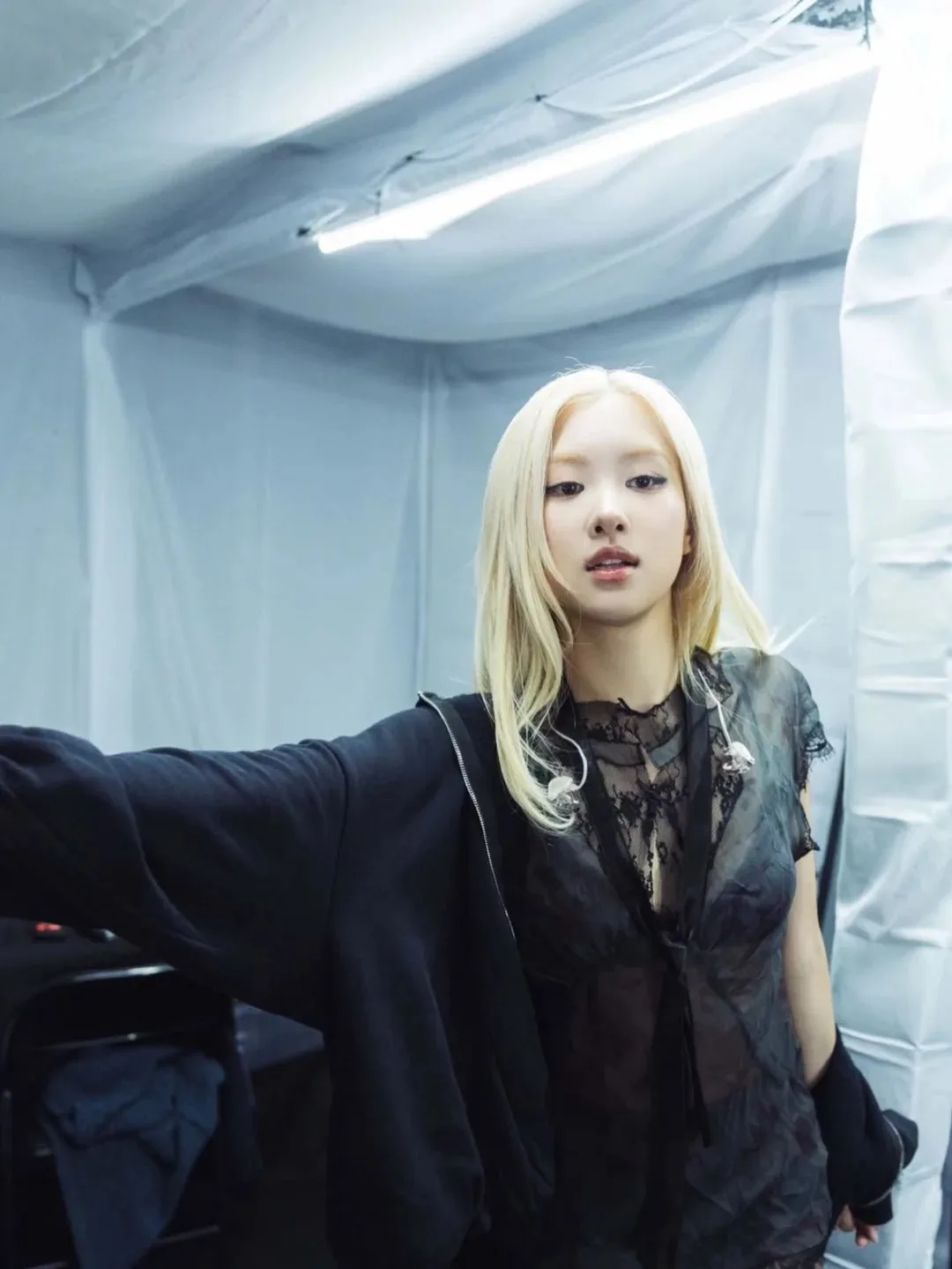 Rosé mặc áo màu đen, tóc màu blonde, background trắng