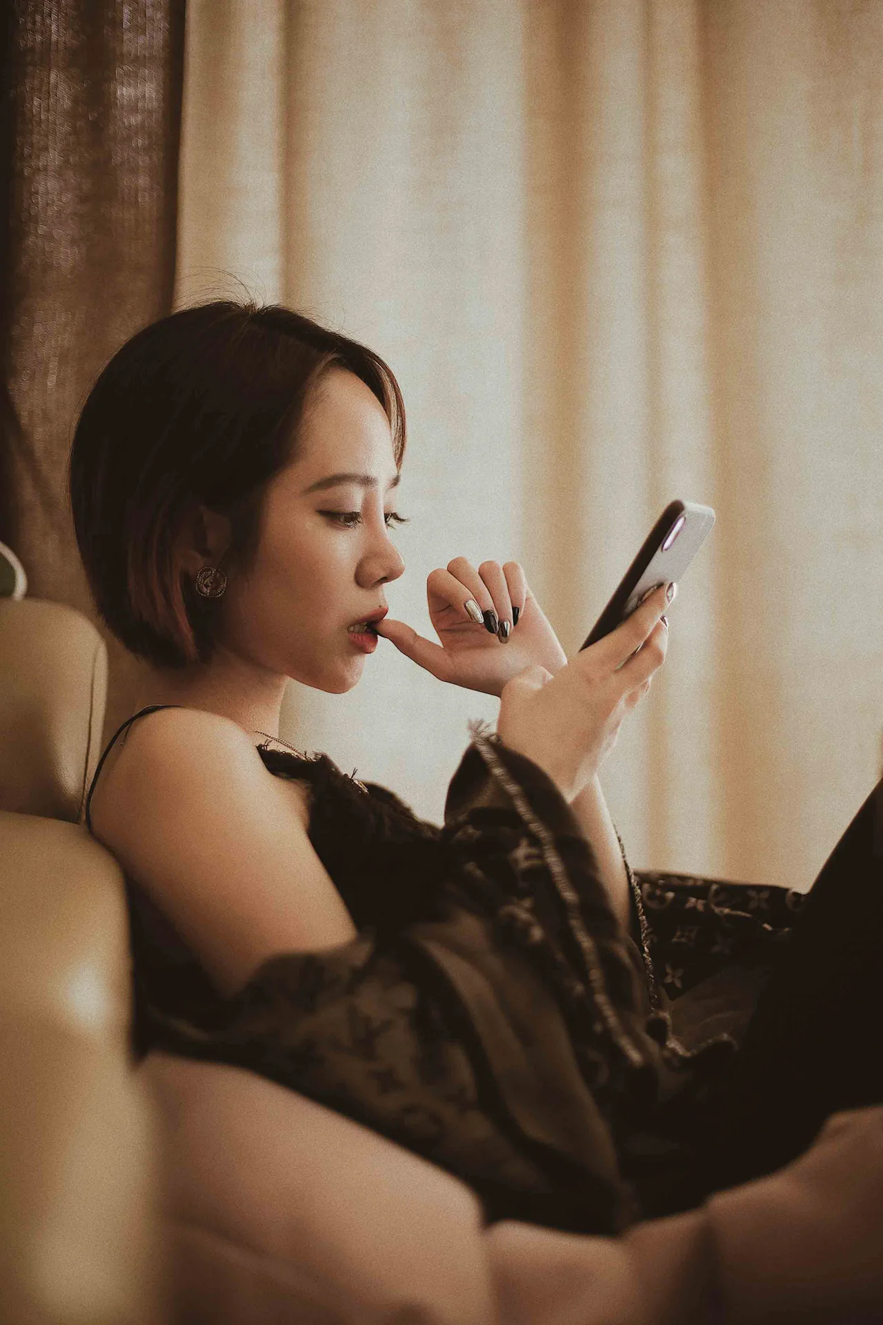 cô gái cắn móng tay cầm điện thoại