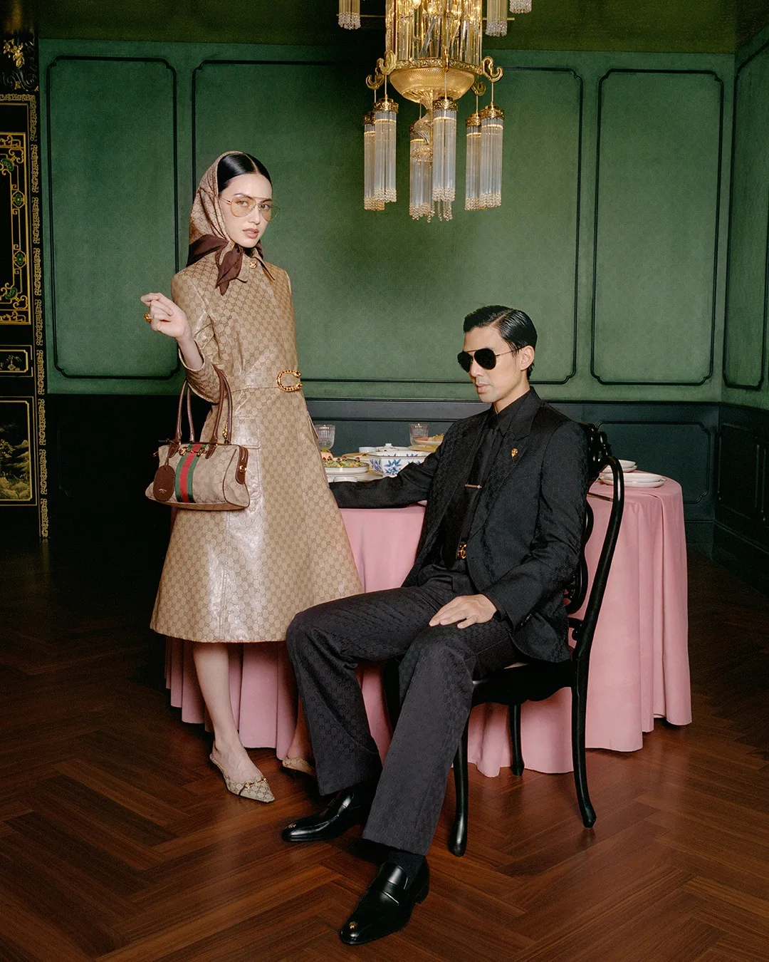 Đại sứ Davika Hoorne đầy cổ điển trong chiếc áo trench coat họa tiết GG Canvas đặc trưng, kết hợp cùng khăn trùm đầu và túi xách Bamboo 1947, bên cạnh ông xã Chantavit Dhanasevi lịch lãm trong bộ suit đen hiện đại.