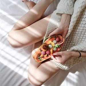 Người mặc đồ len, đặt đĩa trái cây lên chân