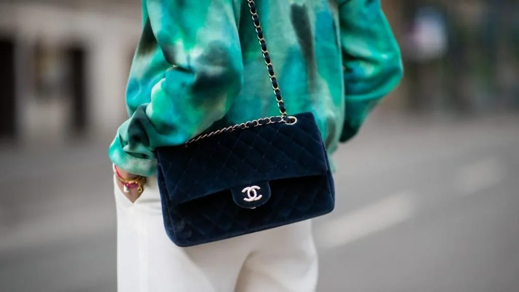 người mẫu mặc áo màu xanh và túi da lộn Chanel