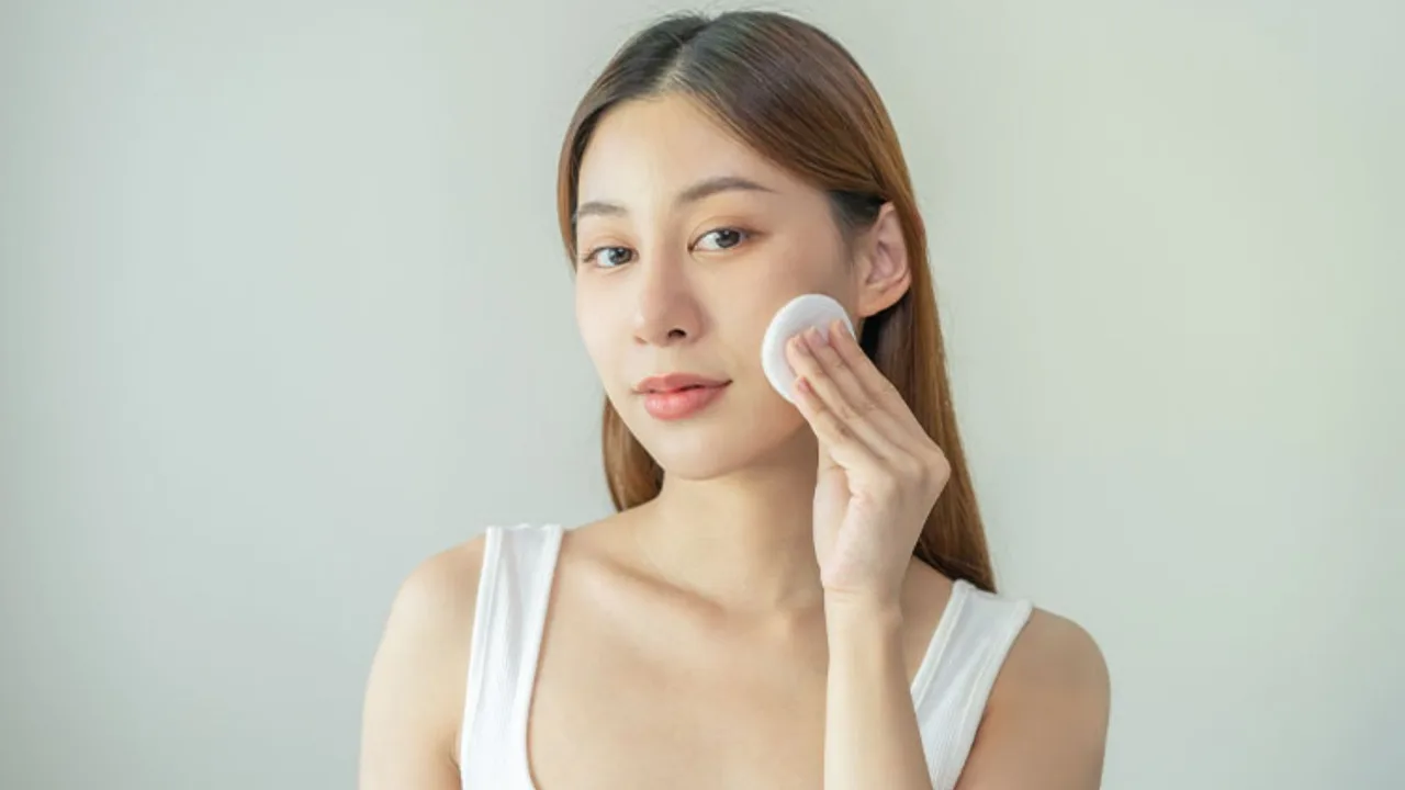 Cô gái đang dùng bông tẩy trang làm sạch da mặt trước khi nặn mụn