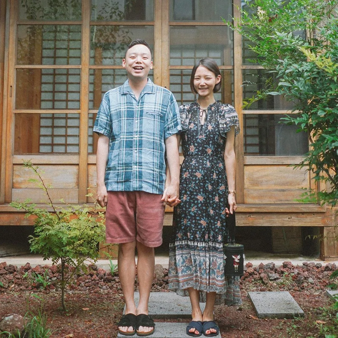 Cặp đôi mặc đồ in họa tiết nắm tay đứng trước nhà