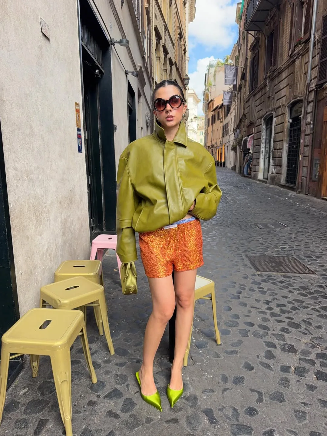 Chiếc áo da màu xanh rêu cá tính kết hợp độc đáo cùng quần shorts sequins màu cam cháy mang lại vẻ ngoài sắc sảo, high-fashion.