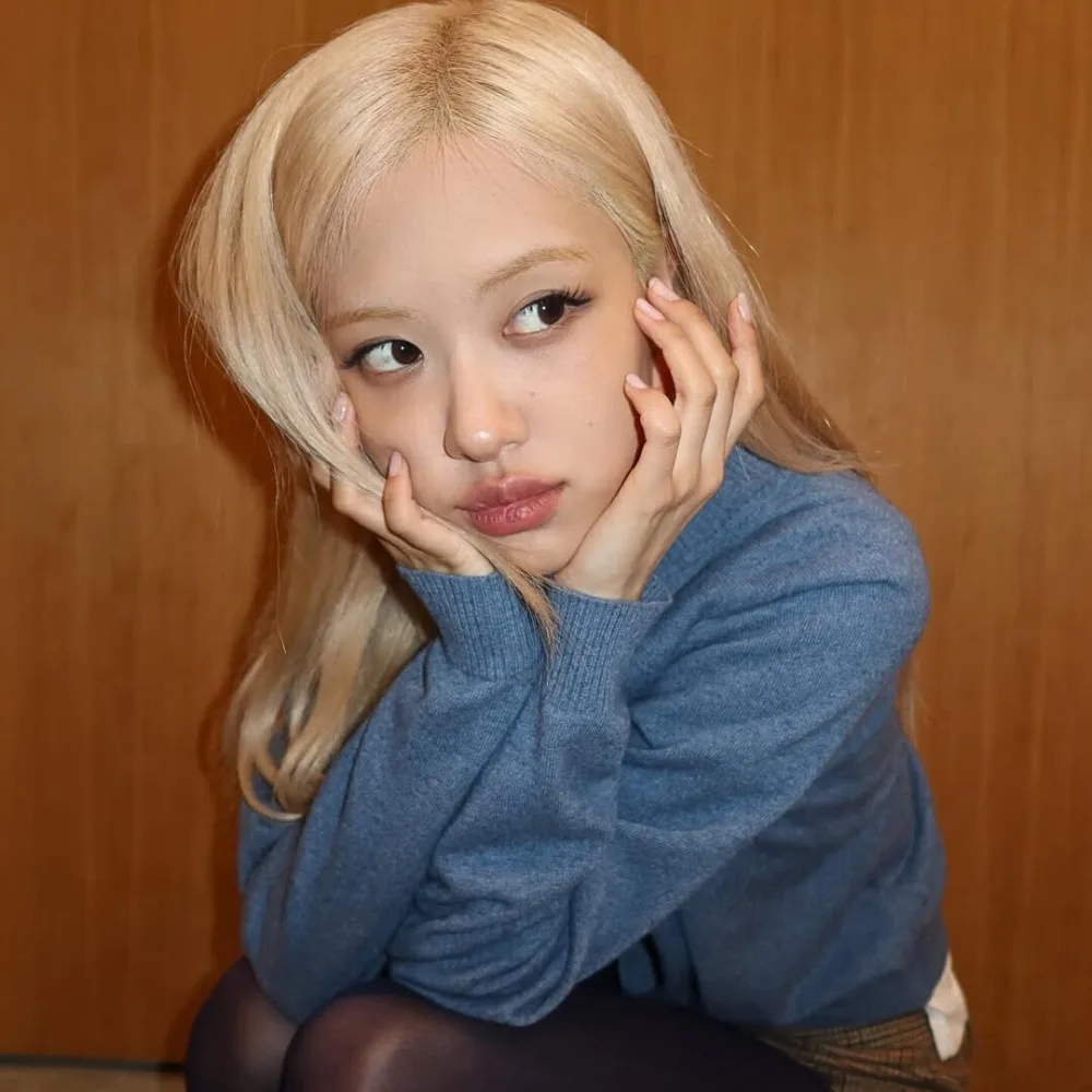 Rosé (BLACKPINK) mang áo xanh dương đang chống 2 tay lên mặt