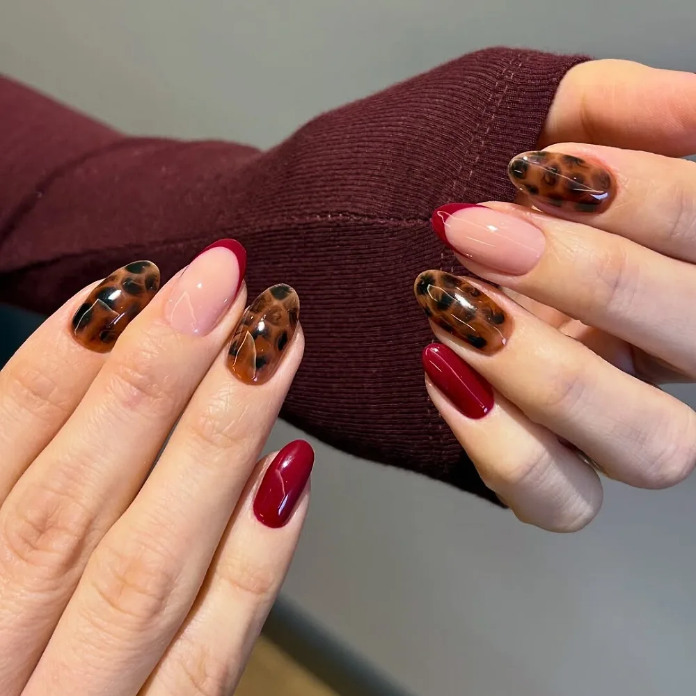 Đôi tay với kiểu nail sơn màu đỏ và nâu