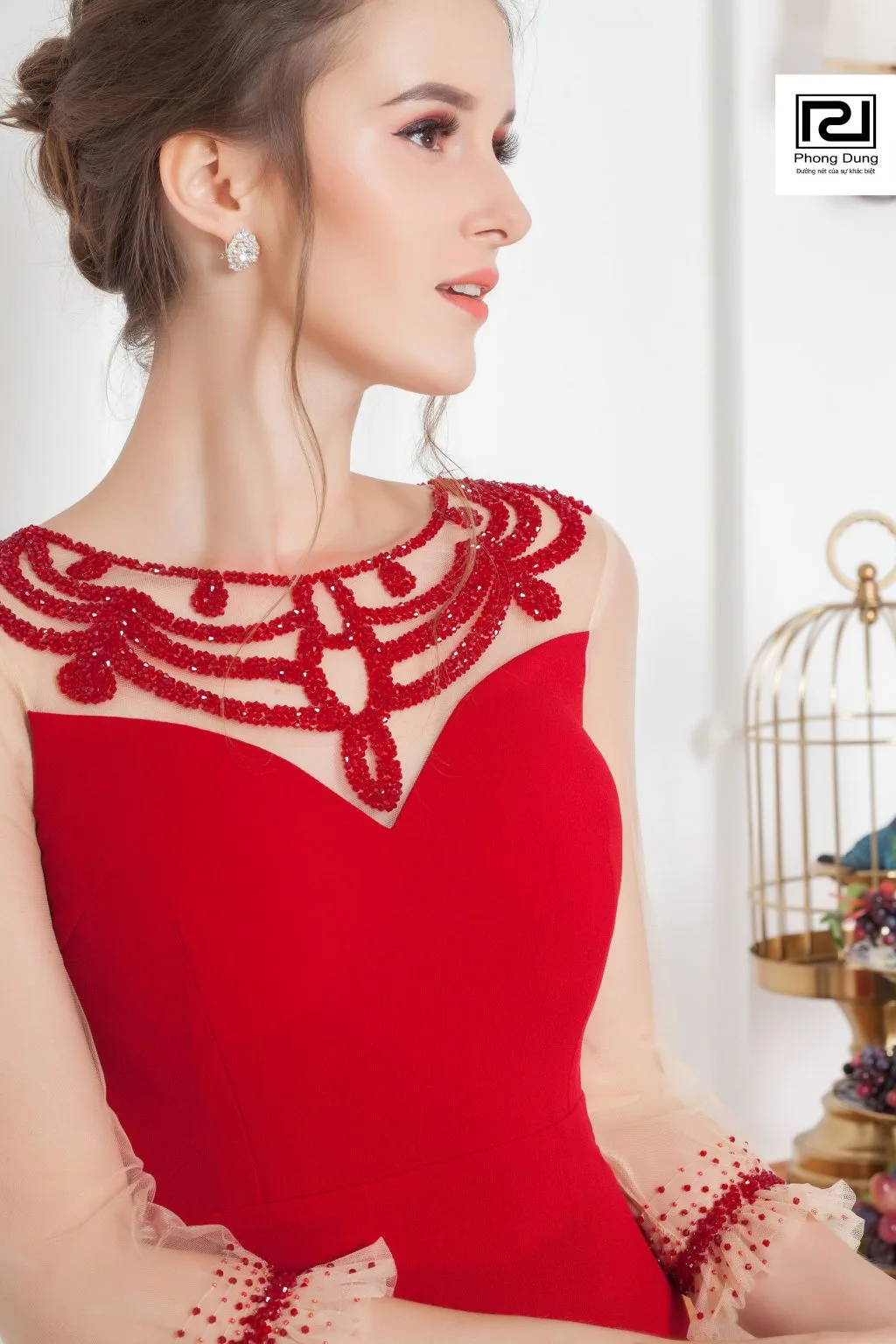 Người mẫu mặc váy ren đỏ mang hoa tai trắng