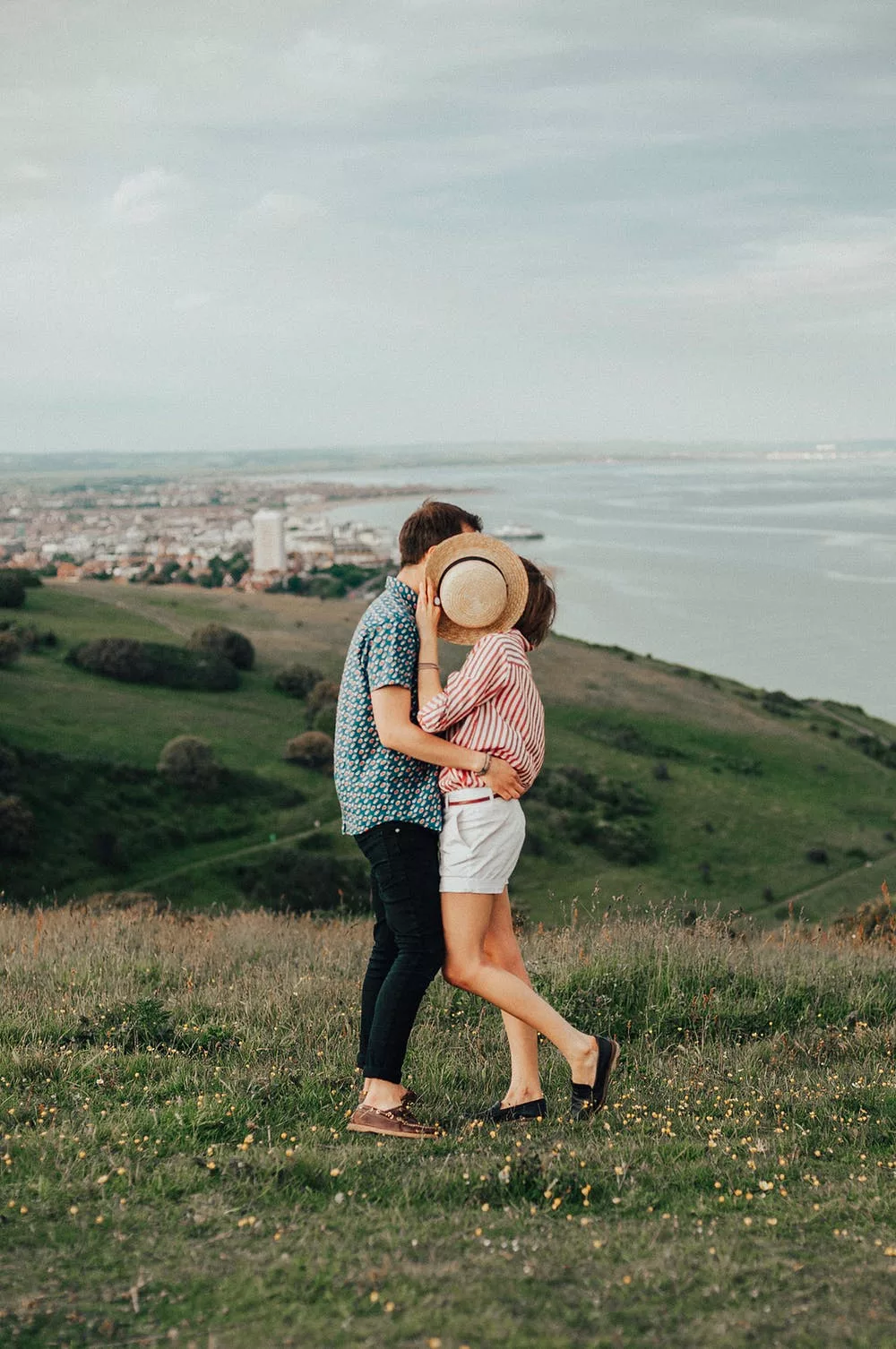 cặp đôi ôm nhau lấy nón che mặt