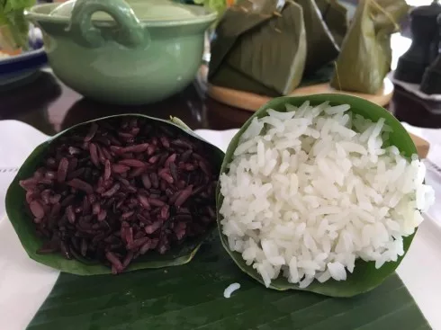 Cơm trắng hoặc xôi nếp cẩm được gói trong lá chuối thành hình chóp nón được phục vụ cùng các món ăn.