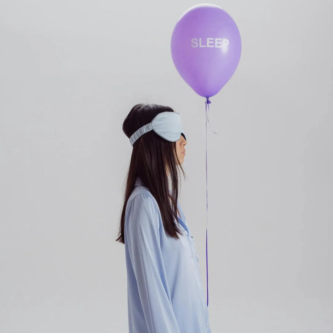 Cô gái trong bộ pijama xanh nhạt cầm bóng bay chữ sleep