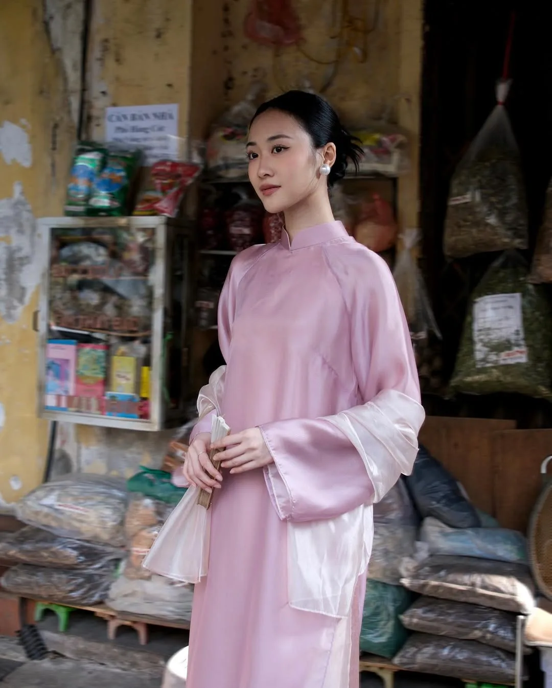Dải lụa thắt hờ ngang eo bay nhẹ trong gió, tạo điểm nhấn mềm mại cho dáng áo dài suông.