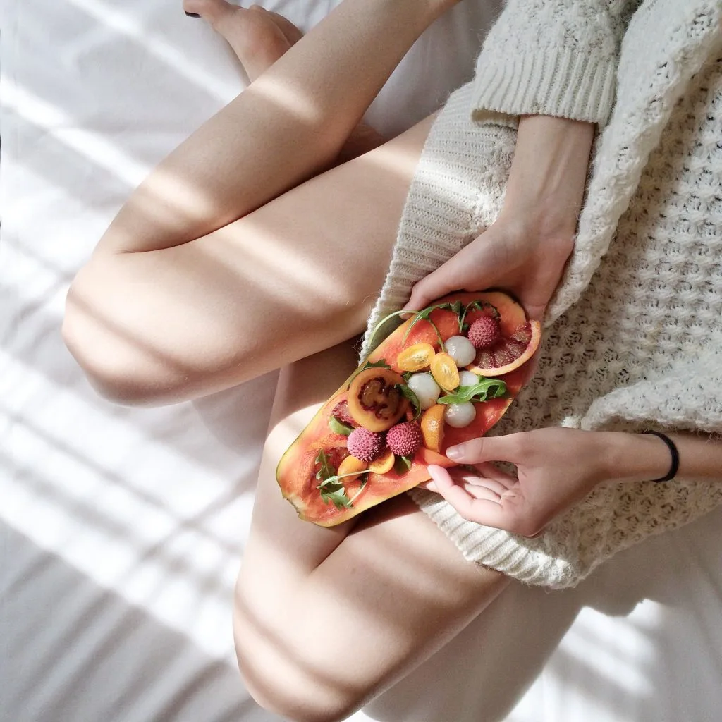 Lối sống lành mạnh. Người mặc đồ len, đặt đĩa trái cây lên chân