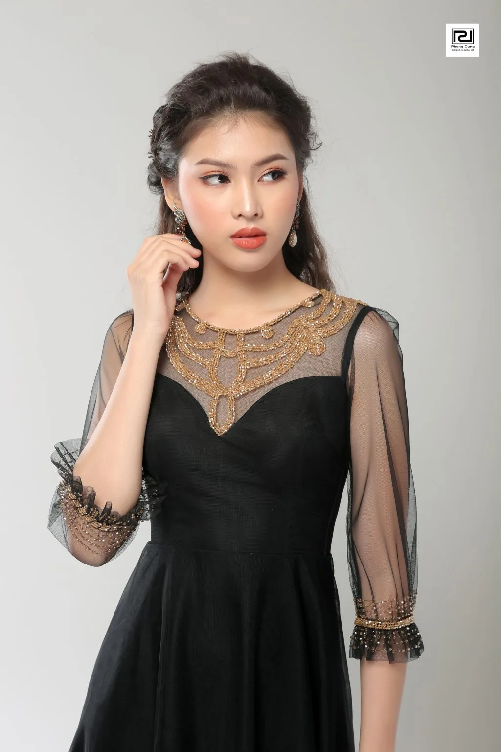 Người mẫu mặc váy đen hoạ tiết ren màu vàng
