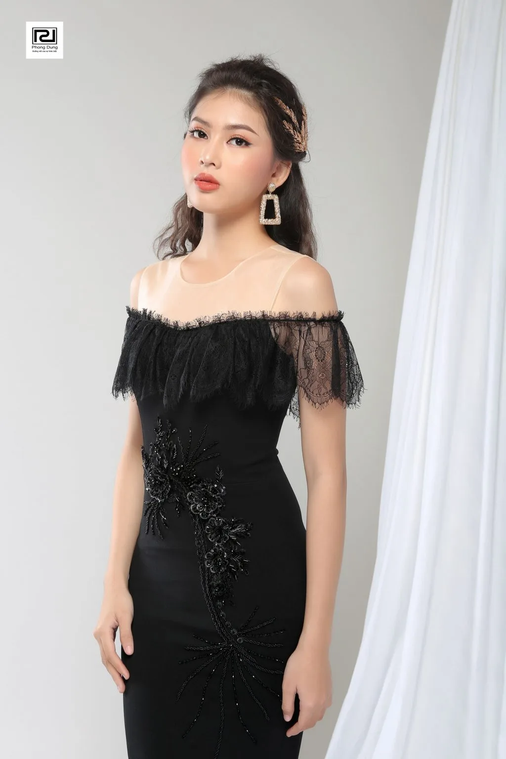 Người mẫu mặc váy hở vai ren đen mang hoa tai hình chữ nhật