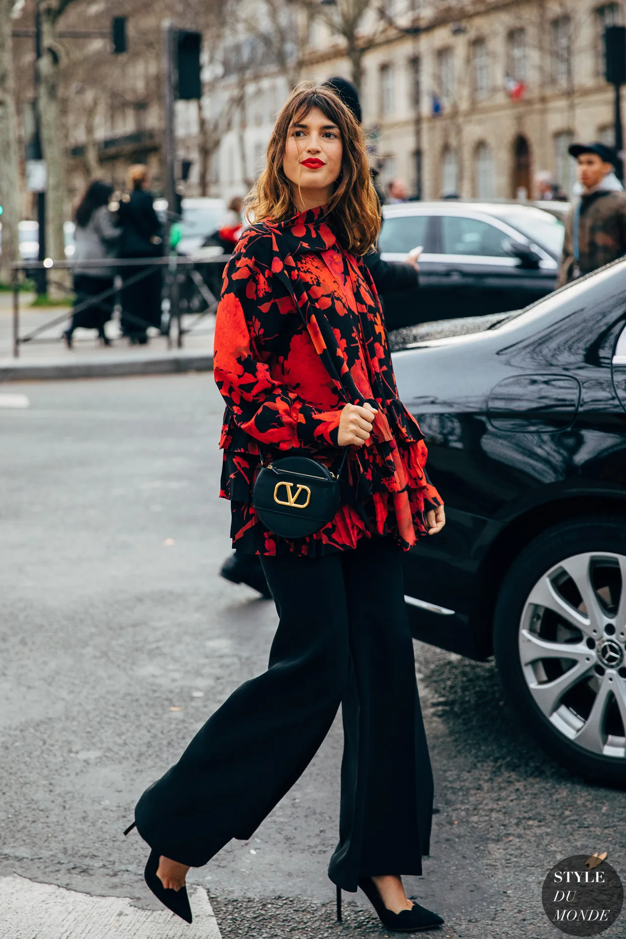 Jeanne Damas diện áo blouse họa tiết hoa đỏ cùng quần cullote đen, giày cao gót và túi xách hình học cùng tông