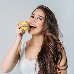 Hình ảnh cô gái đang ăn táo để minh họa cho những món ăn phụ nữ ăn để làm đẹp da.