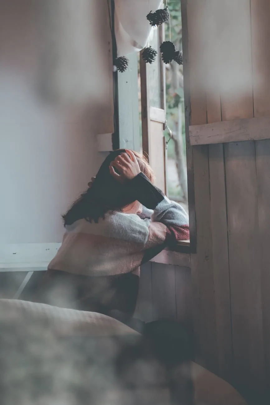 cô gái ngồi chống tay nhìn ra cửa sổ