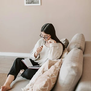 cô gái tóc đen mặc áo trắng ngồi trên sofa lập kế hoạch để thành công