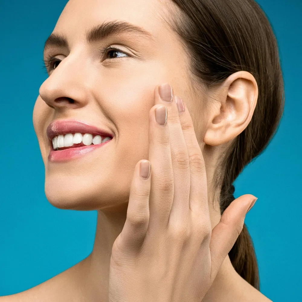 cô gái đang cười, đặt tay lên mặt