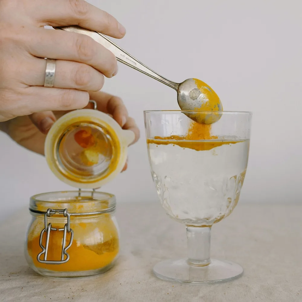 cô gái đang pha bột nghệ vào ly nước