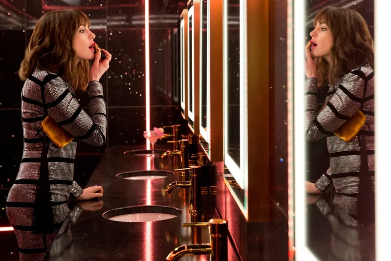 nữ diễn viên Anne Hathaway bôi son trước gương. Cô diện đầm bodycon ánh kim