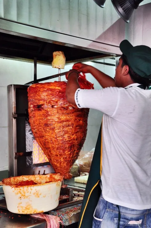 Từng lát thịt heo mỏng tẩm gia vị được đắp lên, làm thành cây Al Pastor.