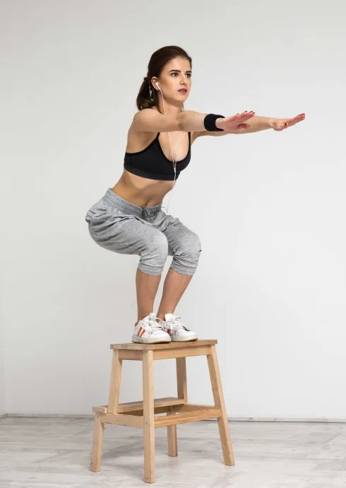 Young healthy woman doing squat exercises