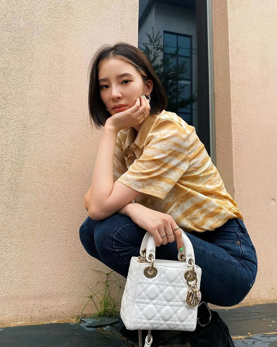 cô gái mặc áo vàng và túi lady dior trắng