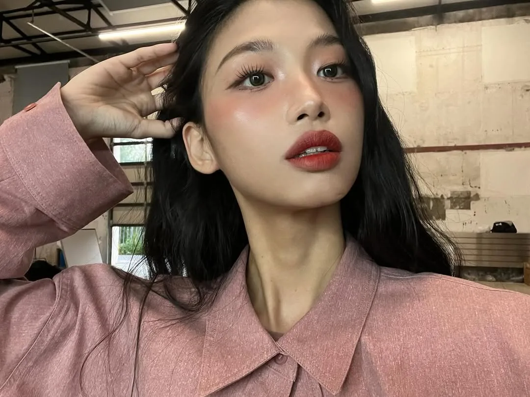 cô gái vén tóc sau tai, trang điểm tone đỏ hồng