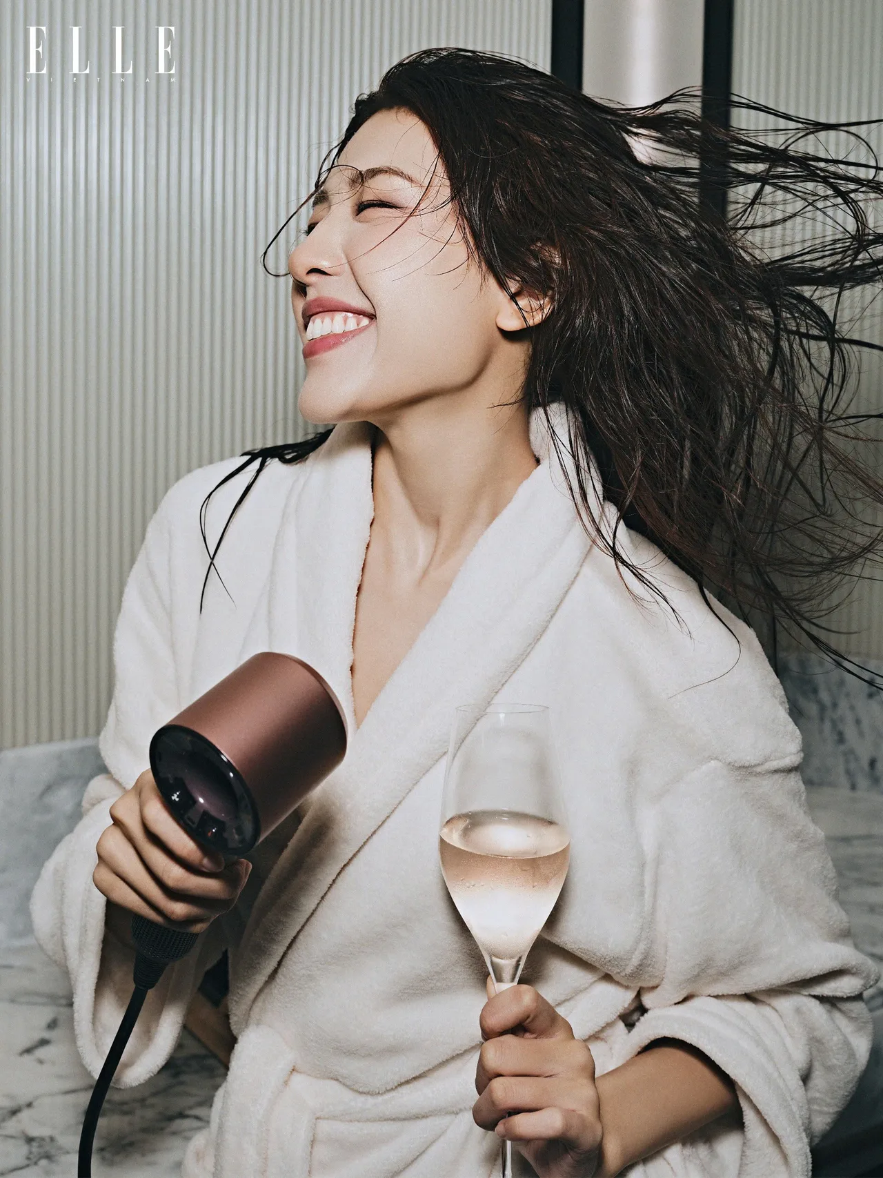 cô gái cầm ly rượu vang đang sấy tóc