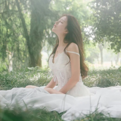 cô gái mặc váy trắng đang ngồi giữa khung cảnh thiên nhiên bình yên.
