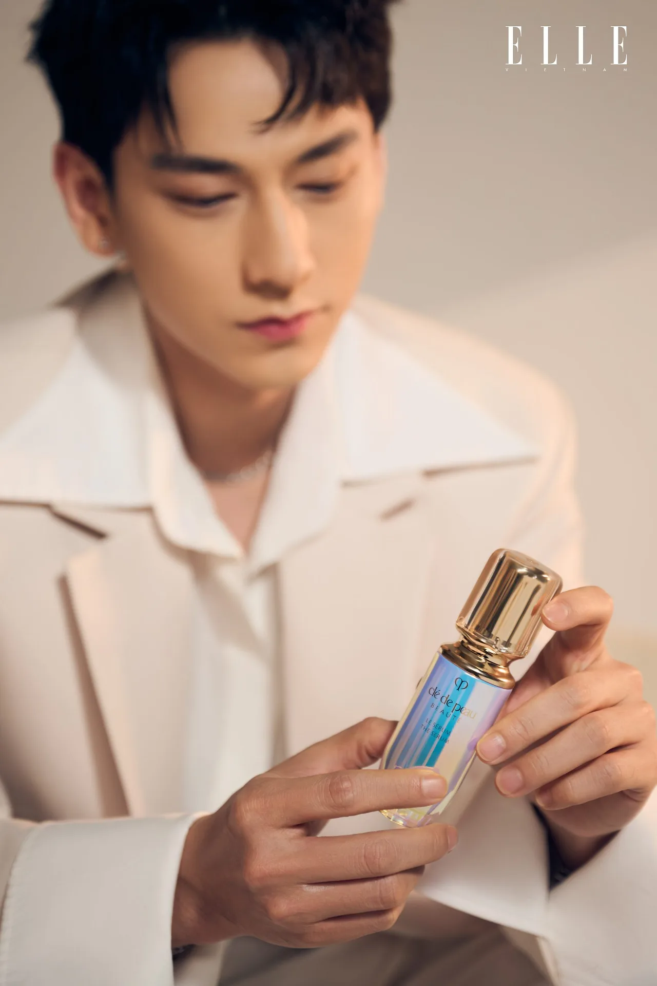 Hình ảnh Isaac cầm sản phẩm Clé de Peau Beauté trên tay.