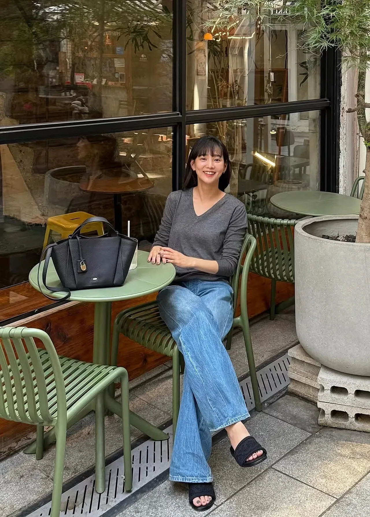 Yoon Seung Ah mặc chiếc áo len cổ chữ V màu xám đơn giản đi cùng quần jeans ống rộng xanh cổ điển và đôi dép quai ngang màu đen