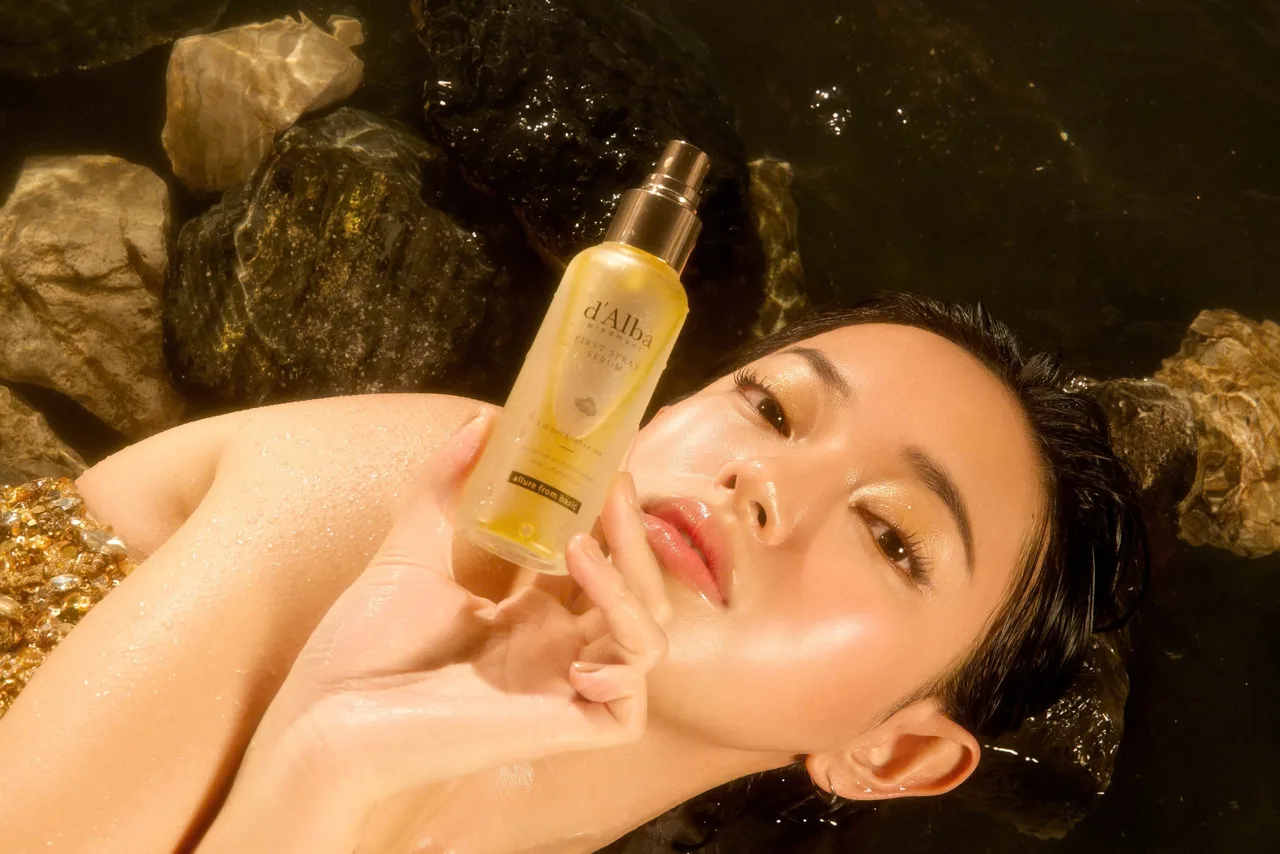 dAlba - fashionista Châu Bùi tạo dáng nằm ngửa và tay cầm chai xịt khoáng serum First Spray Serum