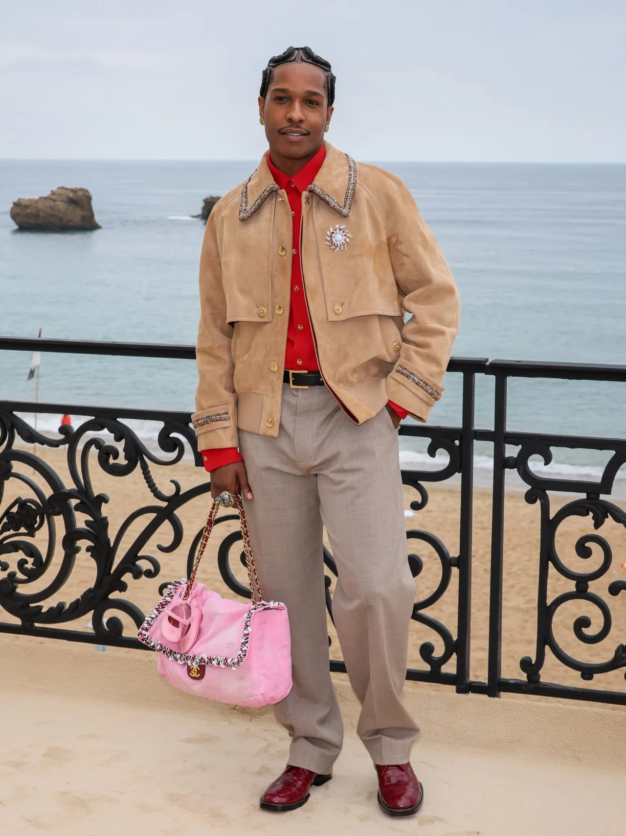 A$AP Rocky lựa chọn jacket dáng rộng và quần suông, giữ bảng màu trung tính. Điểm nhấn nằm ở chiếc túi Chanel được gắn đôi giày ballet nhỏ dành cho con gái.