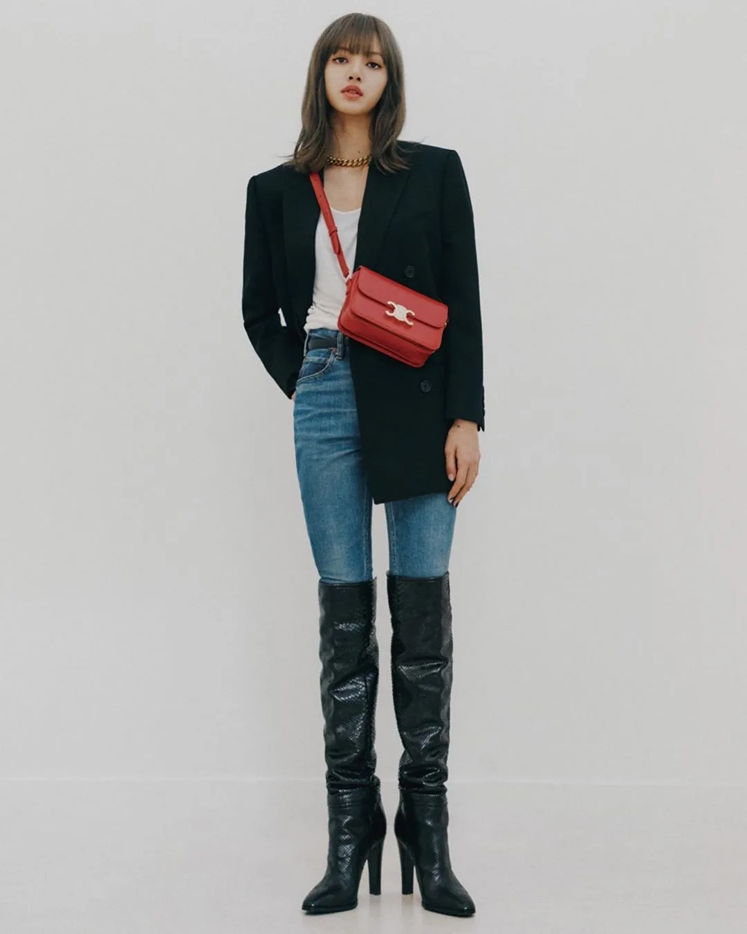 Lisa mặc áo trắng coat đen quần jeans xanh bốt cao cổ đeo túi celine triomphe đỏ