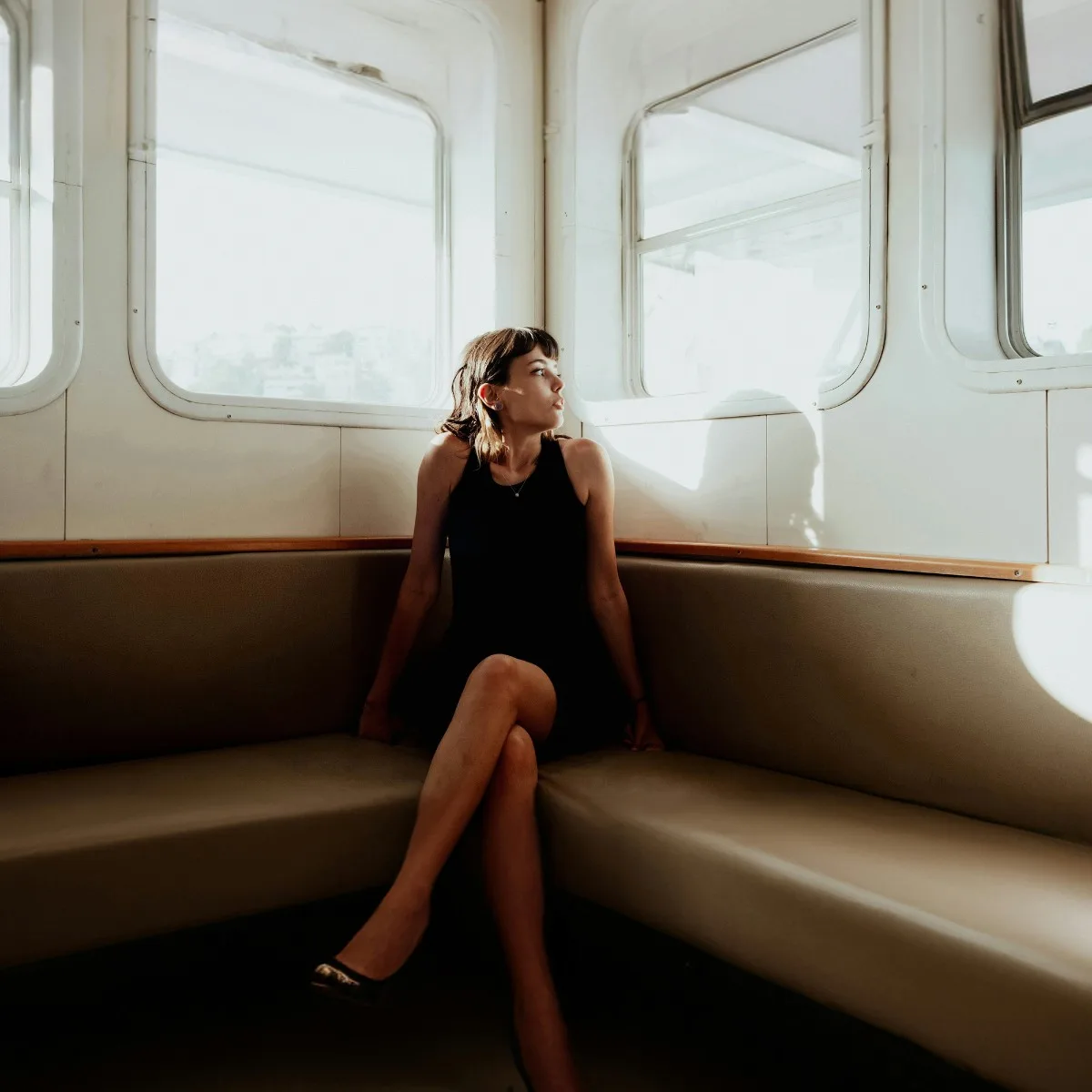Cô gái Gen Z mặc đầm đen ngồi trên ghế sofa nhìn ra cửa sổ